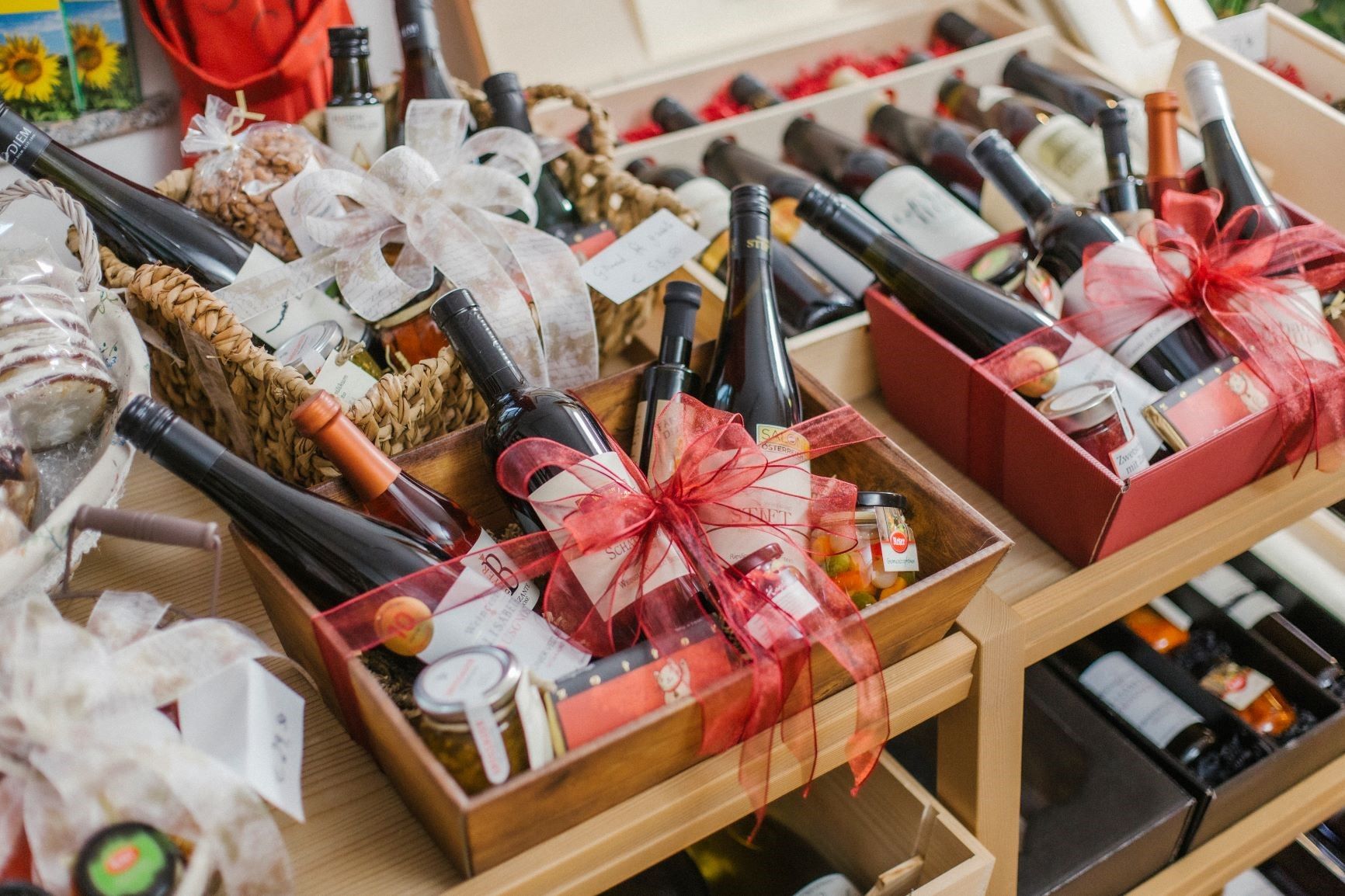 Geschenkboxen mit Weinflaschen und Delikatessen auf einem Tisch.