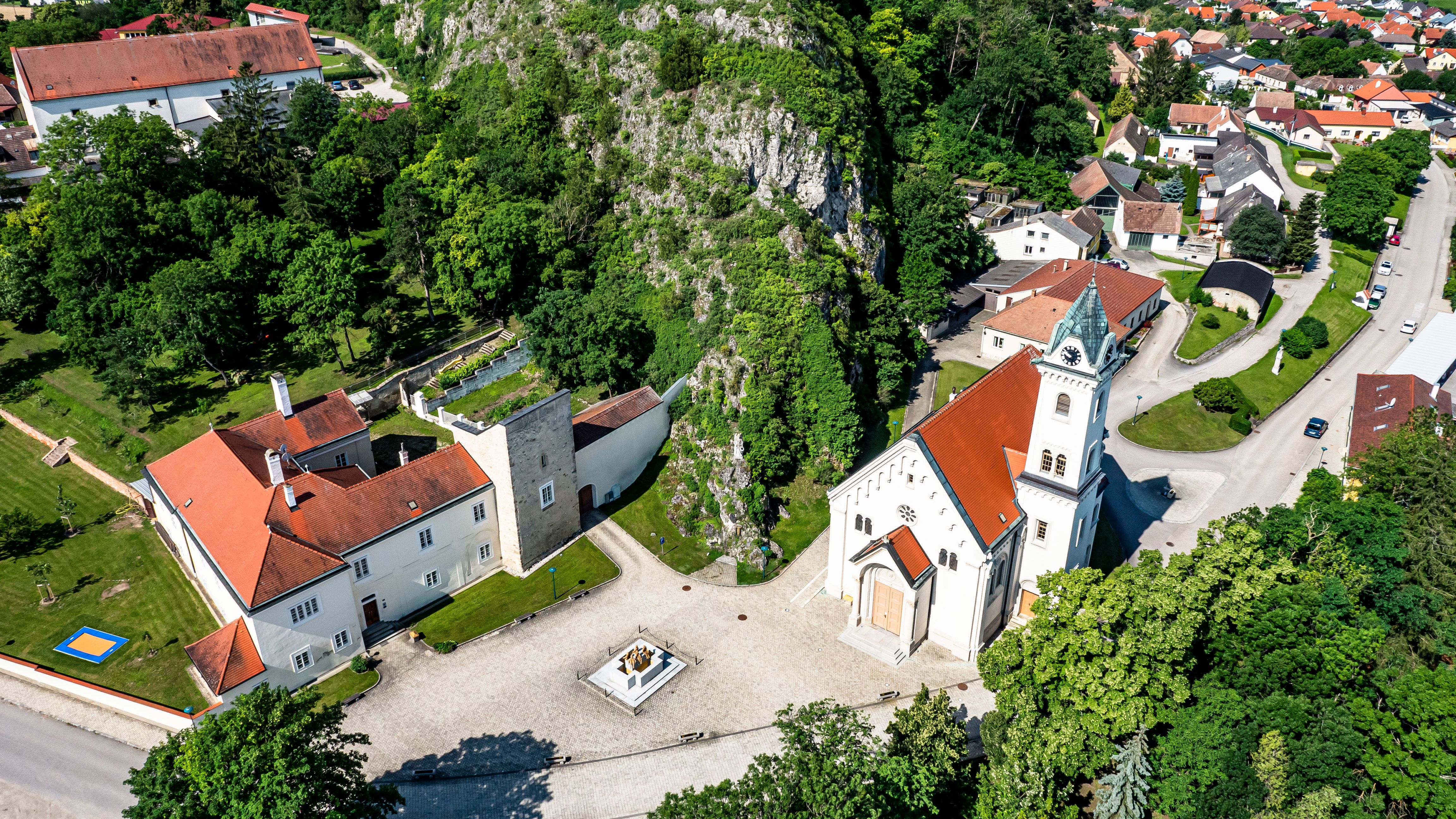 Letecký pohled na farní kostel ve Staatzu s okolními budovami a zelení.