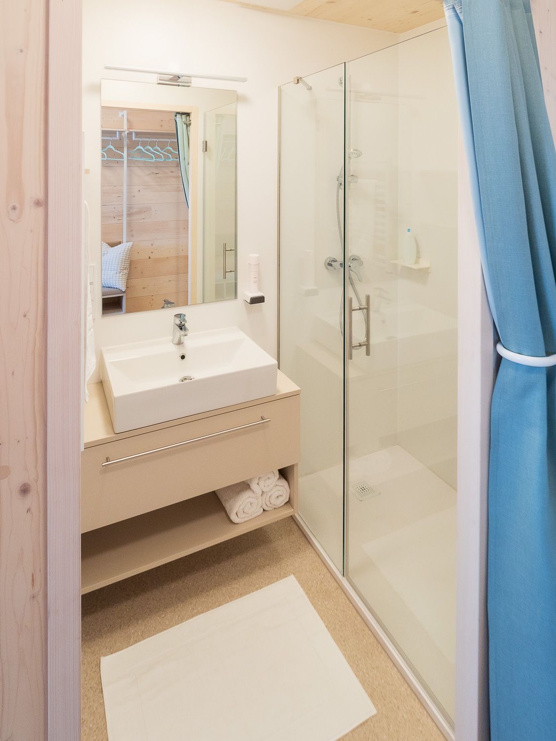 Modernes Badezimmer mit Waschbecken, Spiegel, Dusche und blauen Vorhängen.