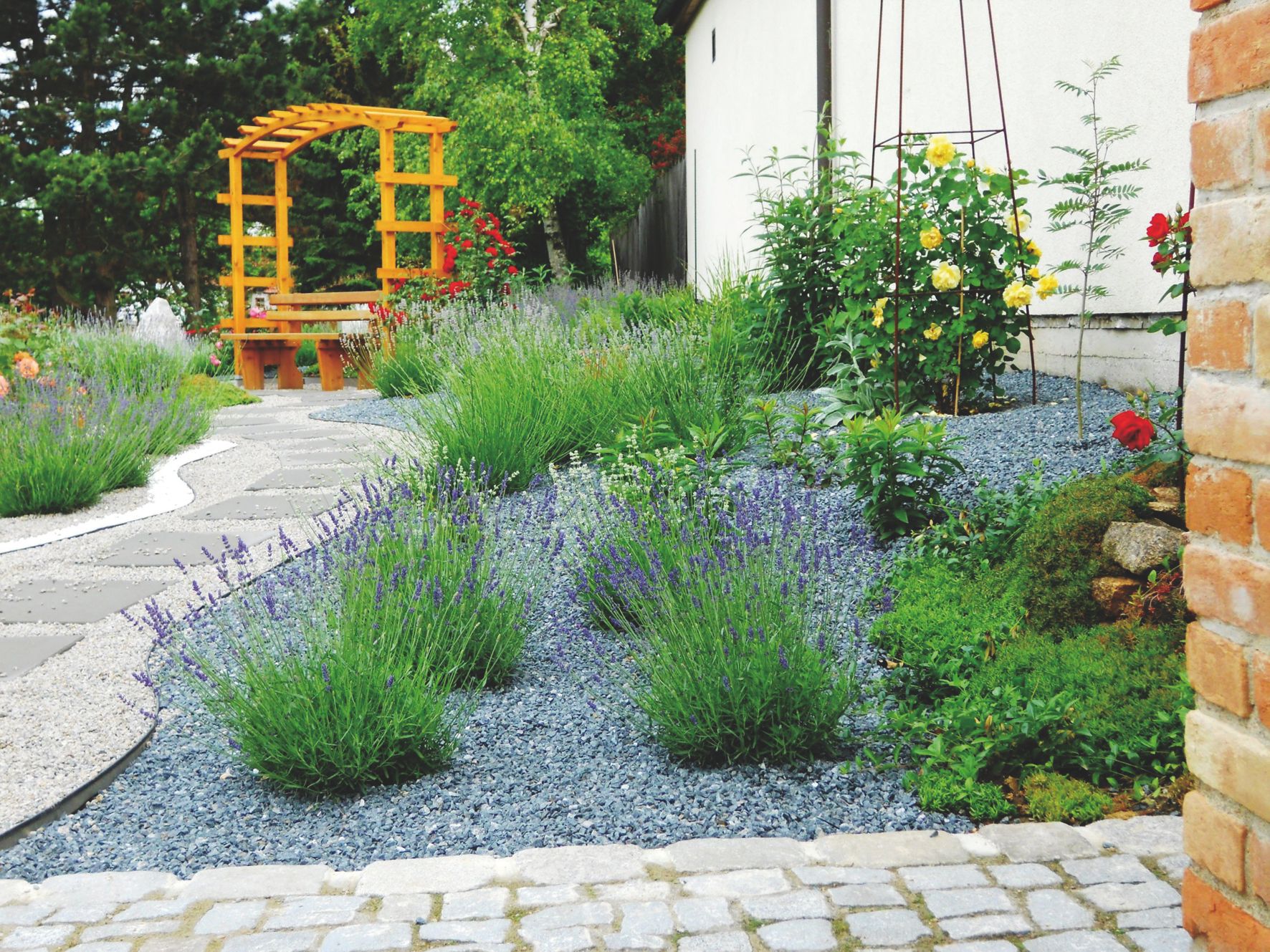 Ein gepflegter Garten mit Lavendel, einem Holzpavillon und gepflasterten Wegen.