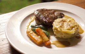 Ein Teller mit Steak, Gemüse und Kartoffelgratin.