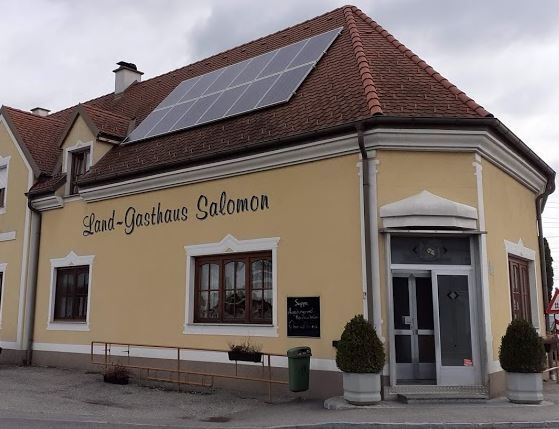 Außenansicht eines traditionellen Landgasthauses mit heller Fassade, roten Fensterläden und Satteldach.
