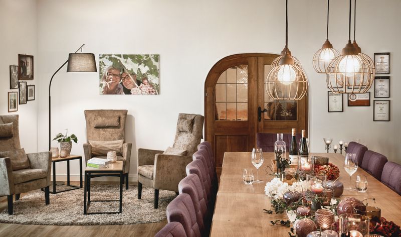 Gemütlicher Verkostungsraum mit Tisch, Stühlen, Sesseln und Dekoration.