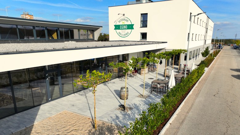 Außenansicht eines modernen Gebäudes mit Terrasse und Pflanzen.