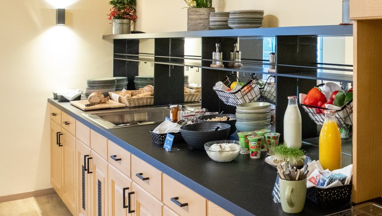 Frühstücksbuffet mit Brot, Joghurt, Saft und Gemüse.
