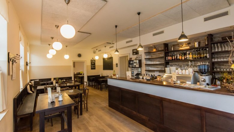 Innenansicht eines gem&uuml;tlichen Wirtshauses mit Holzm&ouml;beln und Theke.