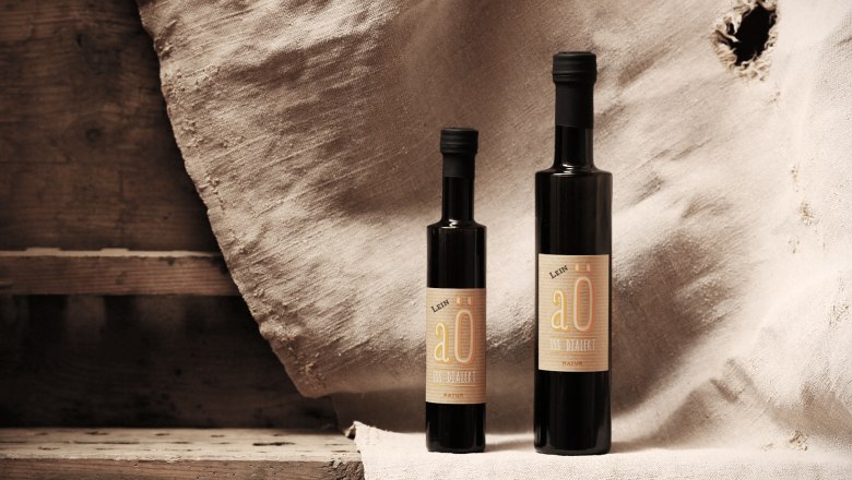 Two bottles of linseed oil in front of a rustic background.