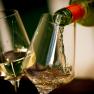 Weißwein wird in ein Glas eingeschenkt, daneben ein weiteres gefülltes Glas.