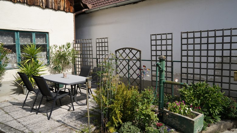 Ein gem&uuml;tlicher Innenhof mit Tisch, St&uuml;hlen und Pflanzen.