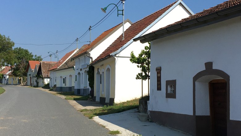 A quiet street with traditional whitewashed houses and red roofs in a rural setting.