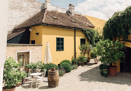 Ein malerischer Innenhof mit gelbem Haus, Pflanzen und Sitzbereich.