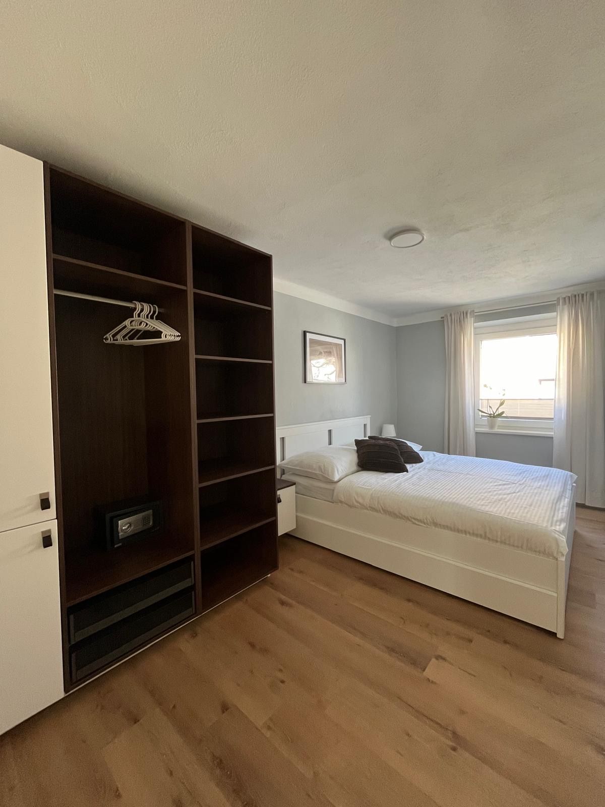 Modernes Schlafzimmer mit Doppelbett, Kleiderschrank und Fenster mit Vorhängen.