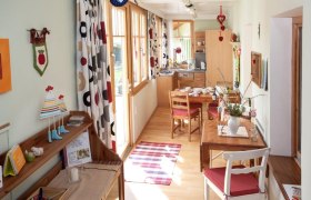 Gemütliche Ferienwohnung mit Holzmöbeln, Esstisch und dekorativen Vorhängen.