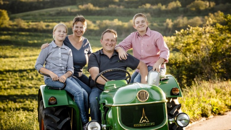 Family on a green tractor in a rural setting.