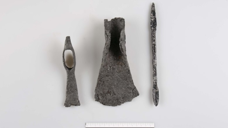 Three archaeological metal objects on a white background with scale at the bottom.