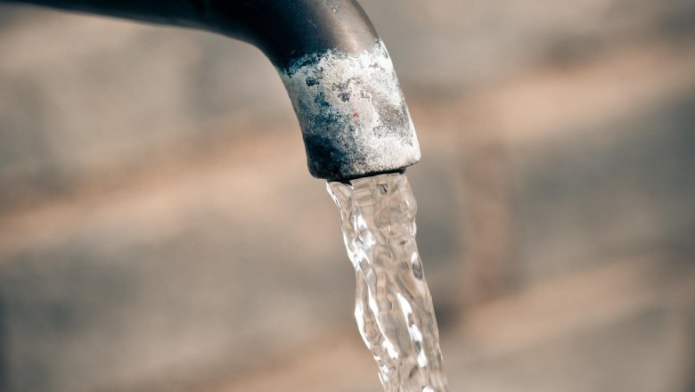 Close-up of a tap with flowing water against a blurred background.