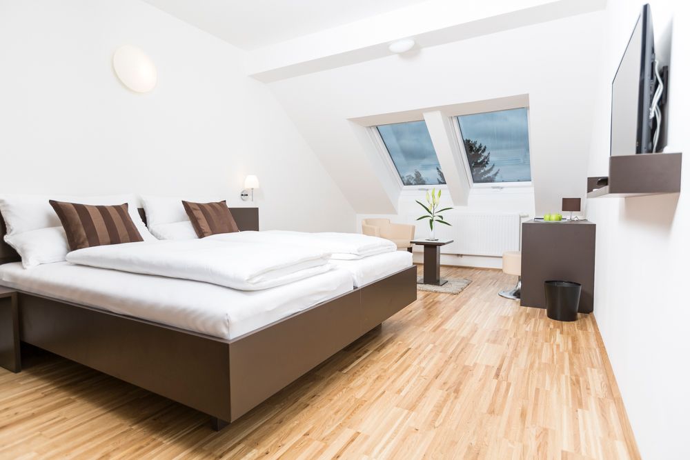 Modernes Gästezimmer mit Doppelbett, Dachfenstern und Holzboden.
