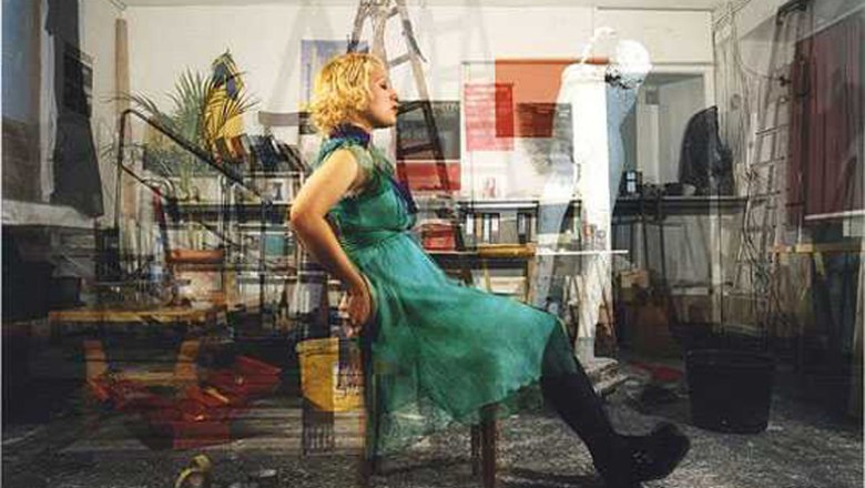 Eine Frau in einem grünen Kleid sitzt in einem überfüllten Raum auf einem Stuhl.