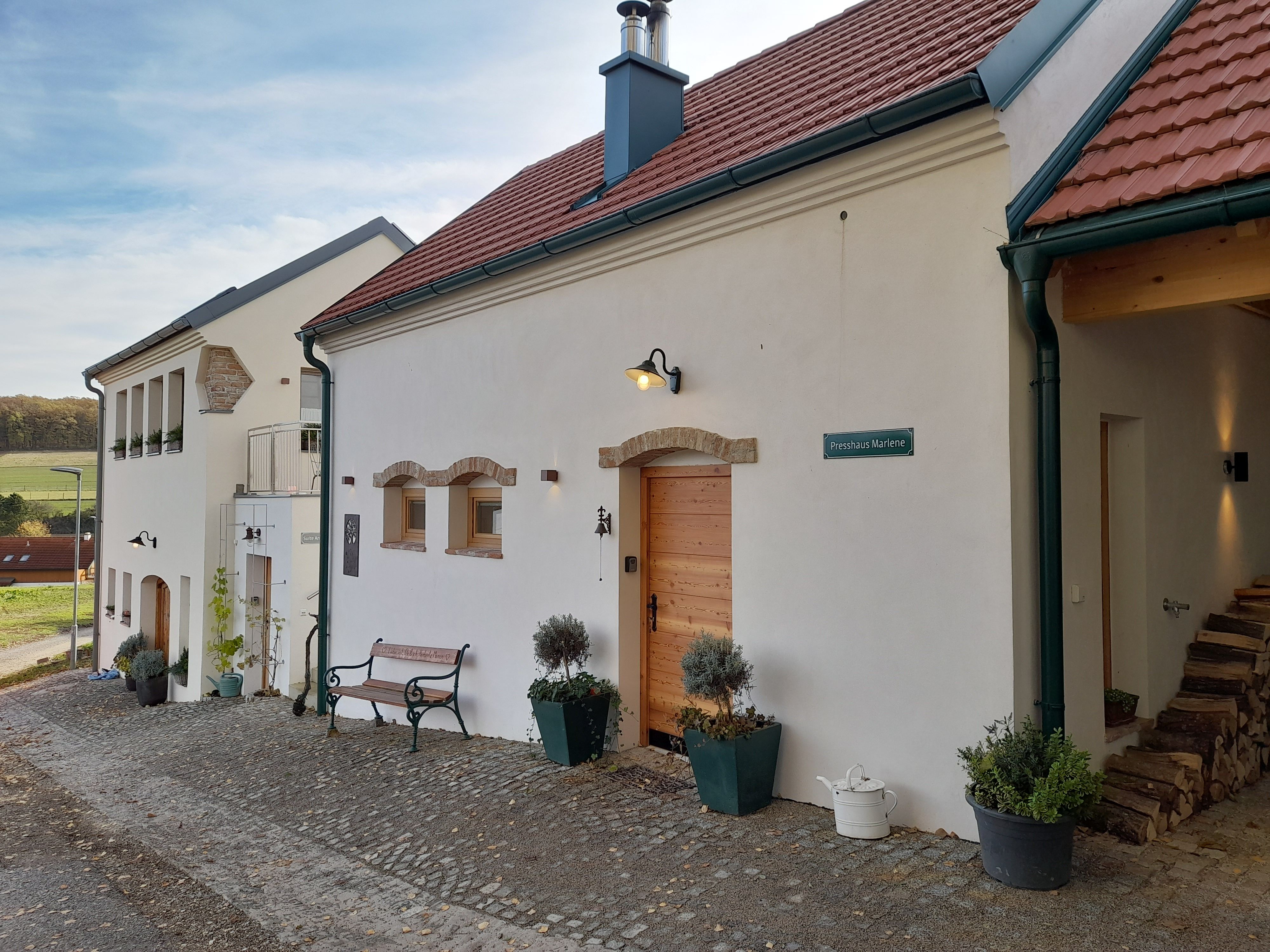 Ein renoviertes Gebäude mit roten Ziegeldächern und weißer Fassade auf einem Biohof.