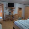 Comfortable bedroom with wooden furniture, double bed, desk and TV.