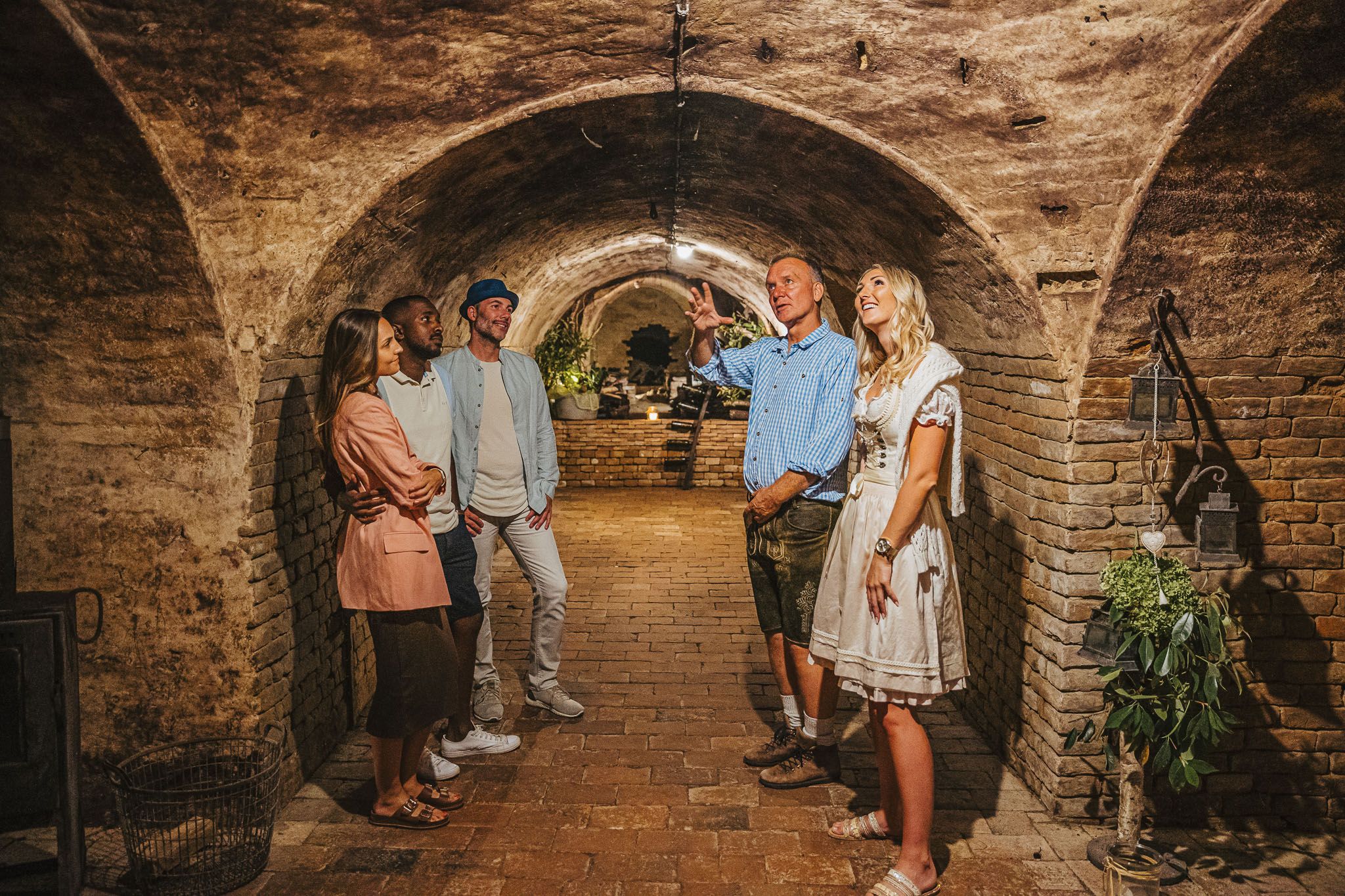 Vier Personen stehen im Gewölbekeller des Winzerhofs Küssler; ein Mann erklärt etwas, während die anderen zuhören.