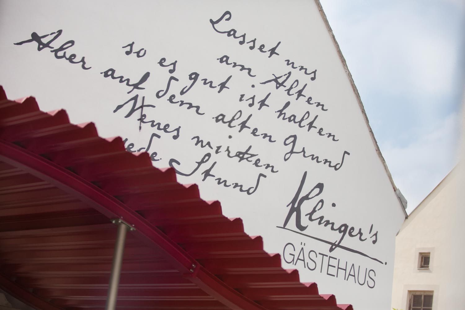Fassade von Klinger's Gästehaus mit handgeschriebener Inschrift und rotem Vordach.