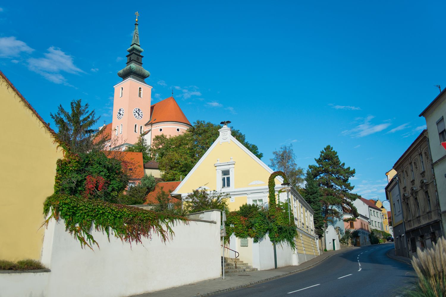 Straße in Poysdorf mit Kirche im Hintergrund und blauen Himmel.