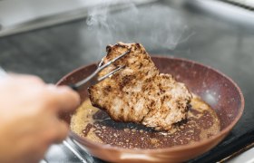 Ein Stück Fleisch wird in einer Pfanne gebraten.