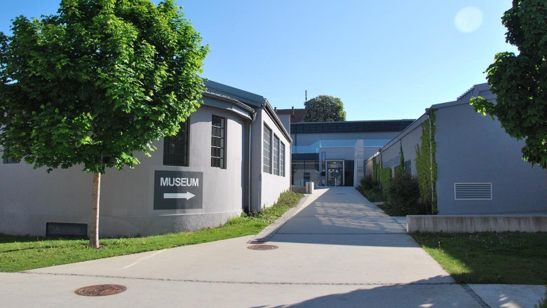 Eingang des MAMUZ Museums Mistelbach mit Wegweiser und B&auml;umen.