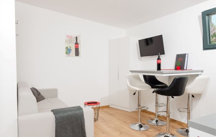 Modernes Wohnzimmer mit Sofa, Esstisch und Barhockern.