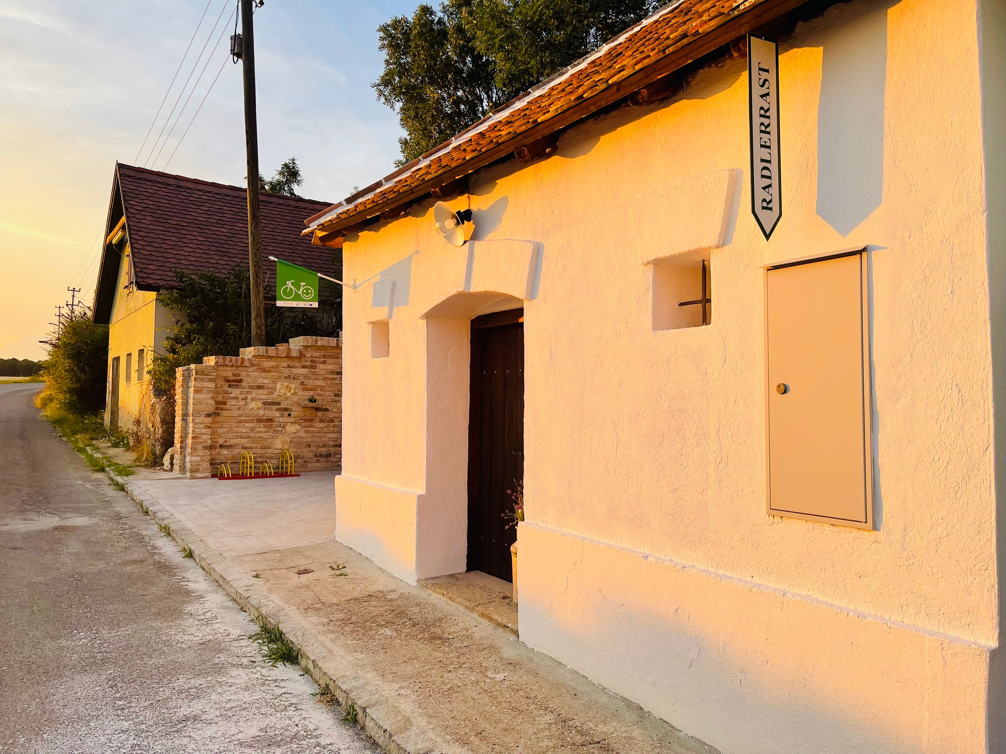 Exterior view of a cellar with sign 'Radlerrast' at sunset.