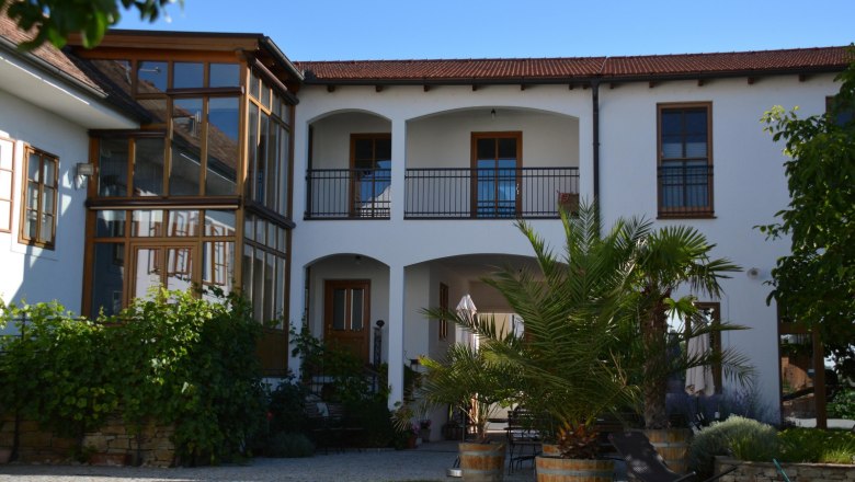 Innenhof eines Weinguts mit Pflanzen und Sitzbereich.