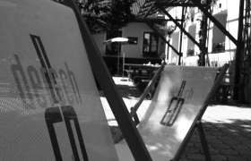 Schwarz-weiß Foto von Liegestühlen im Freien vor einem Gebäude.