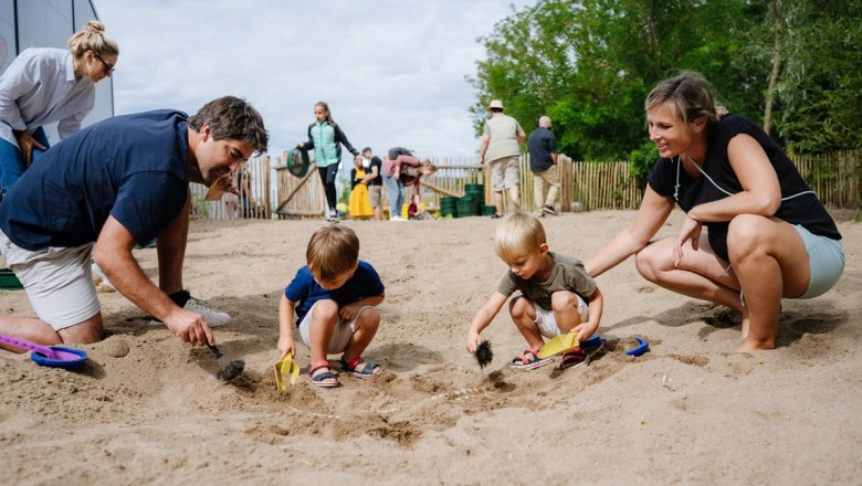 Families dig in the sand for fossils in an open-air museum.
