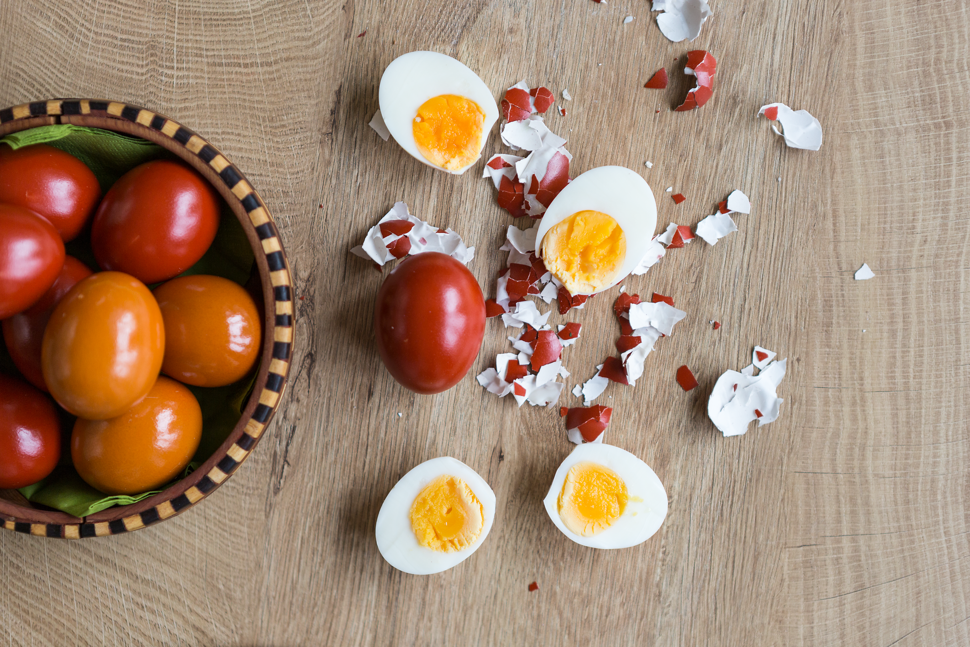Frisch gekochte Eier, perfekt zubereitet, liegen auf einem rustikalen Holztisch, umgeben von zerbrochenen Eierschalen. Neben ihnen glänzen saftige, rote Tomaten in einer traditionellen Schüssel. Diese Szene verkörpert die herzliche Gastfreundschaft und die kulinarischen Köstlichkeiten der Region.