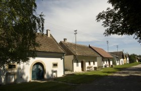Reihe von Weinkellern in Schöngrabern, Österreich, bei sonnigem Wetter.