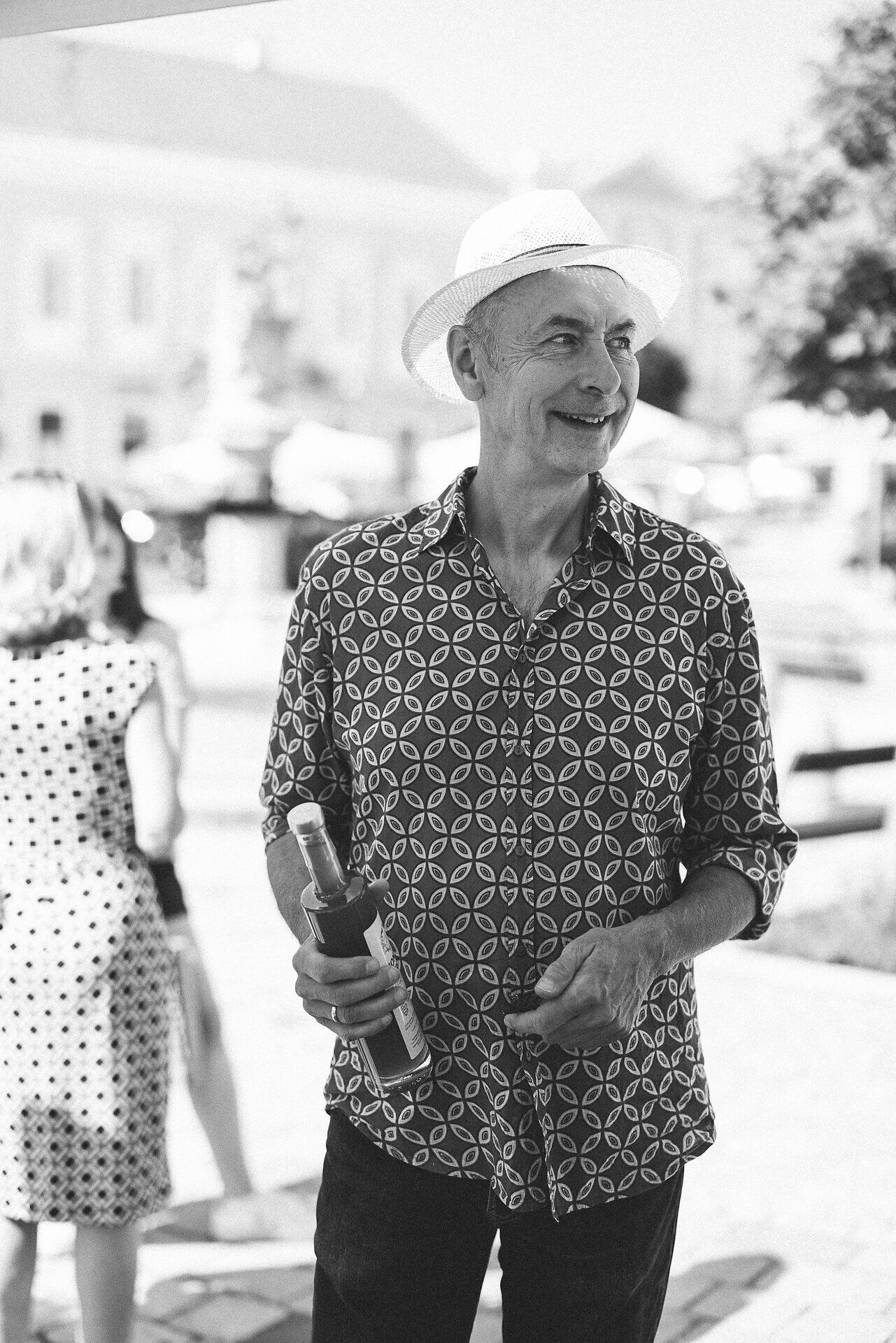 Ein fröhlicher Mann mit einem breiten Lächeln und einem Strohhut genießt die Atmosphäre des Genussmarktes. Um ihn herum pulsieren die Farben und Aromen regionaler Köstlichkeiten, während die Sonne sanft auf die lebhaften Stände scheint. Hier im Weinviertel wird der Herbst mit all seinen Genüssen gefeiert.