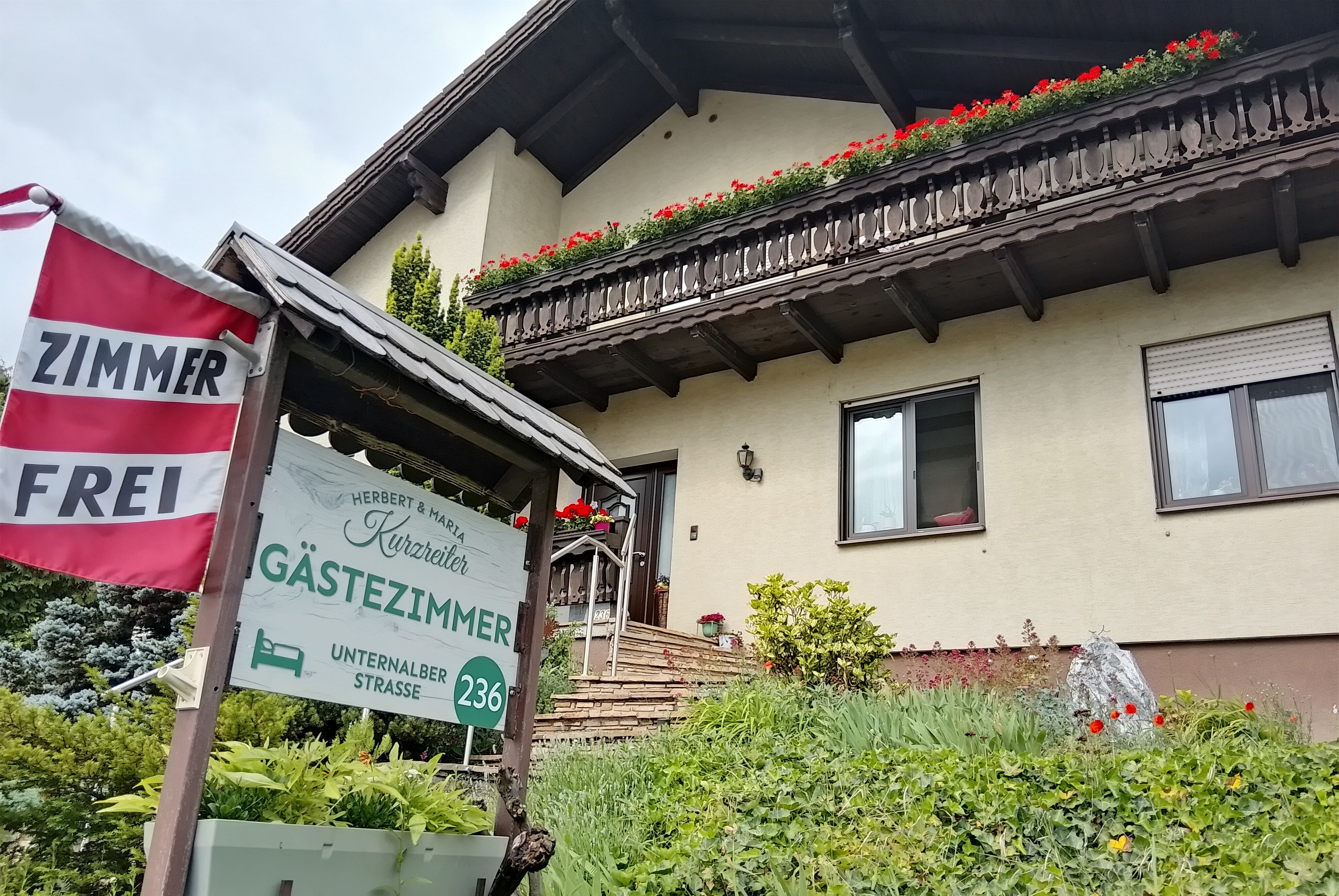 Außenansicht eines Gästehauses mit einem Schild, das "Gästezimmer" und "Zimmer frei" anzeigt.