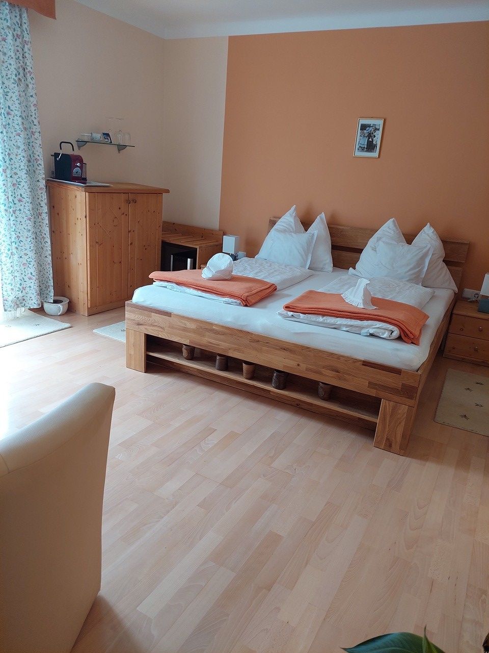 Gemütliches Schlafzimmer mit Doppelbett, Holzmöbeln und oranger Wand.