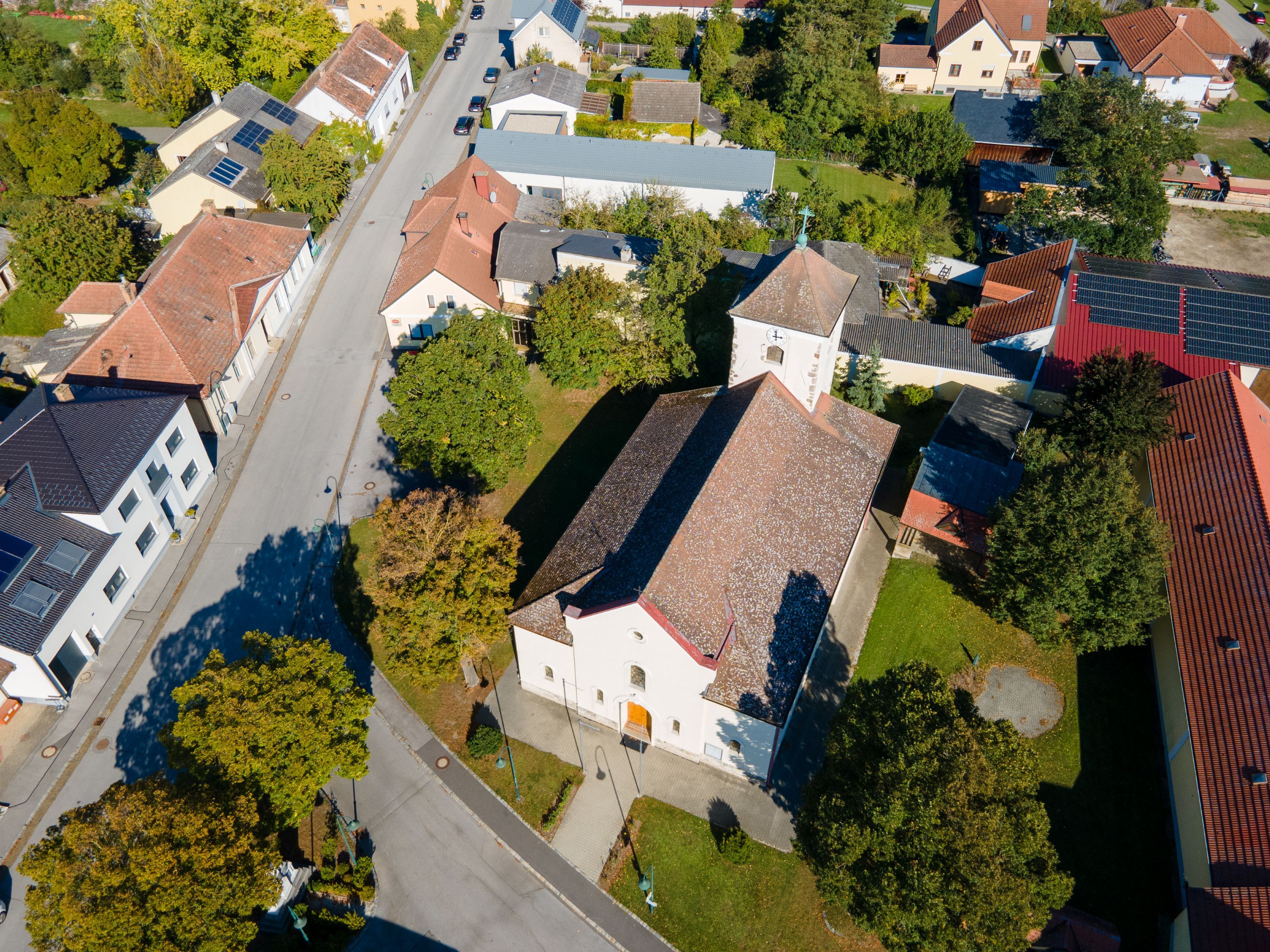 Luftaufnahme der Gemeinde Weiden an der March mit Kirche, Wohnhäusern, Straßen und viel Grün.