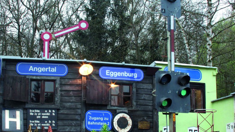 Modelleisenbahn mit Z&uuml;gen vor einem kleinen Geb&auml;ude mit Schildern 'Angertal' und 'Eggenburg'.