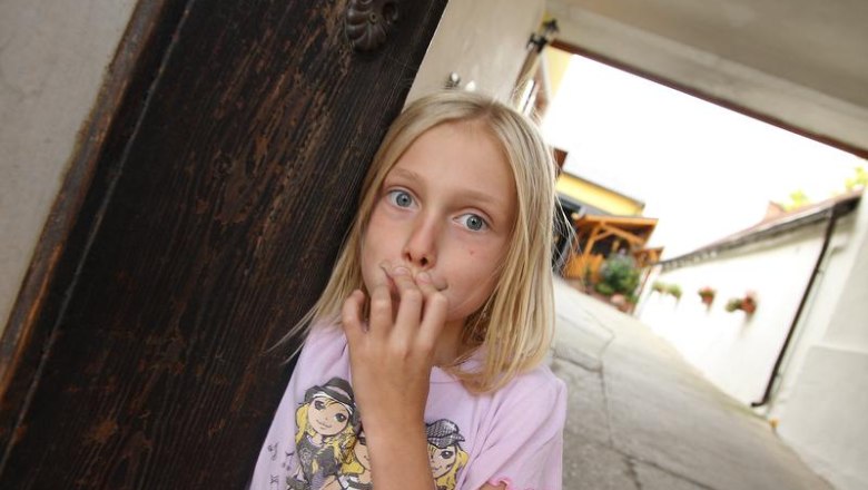 Ein Mädchen steht in einem Torbogen und schaut überrascht in die Kamera.