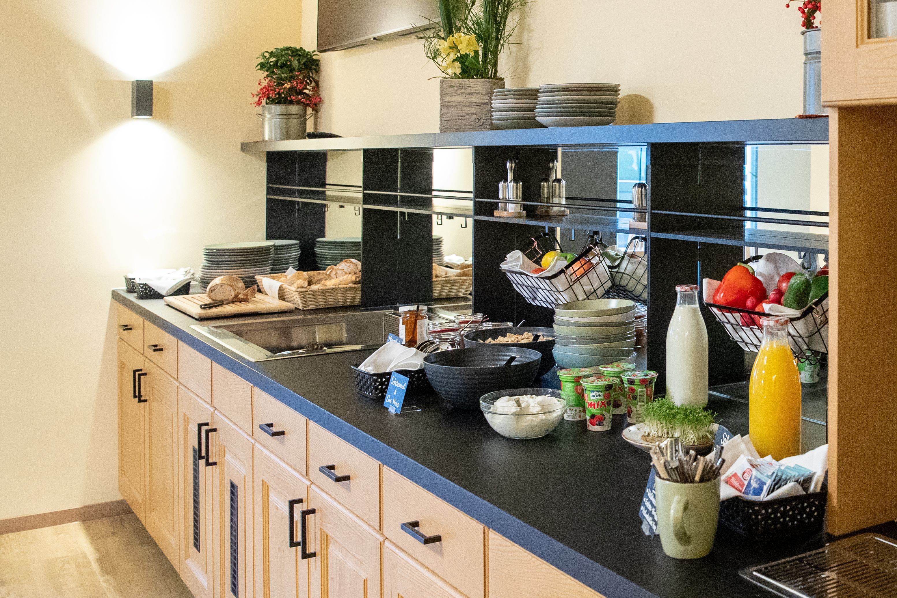 Frühstücksbuffet mit Brot, Joghurt, Saft und Gemüse.