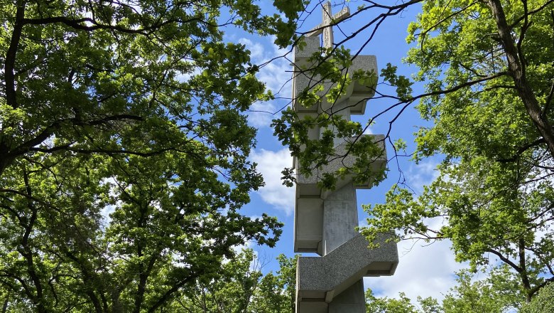 Ein moderner Aussichtsturm in einem Waldgebiet mit blauem Himmel.