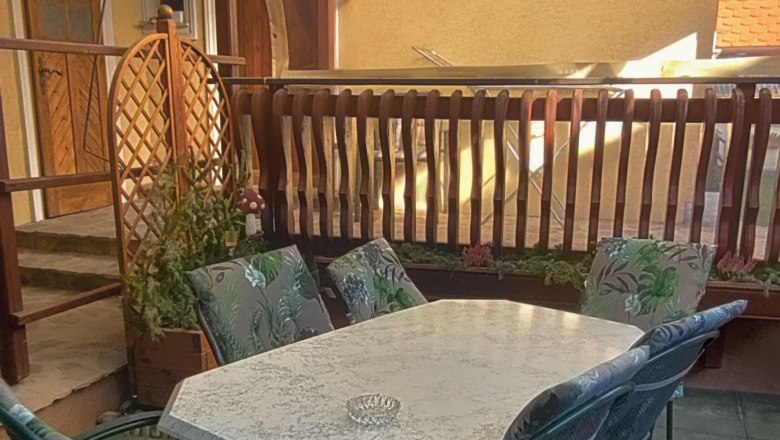 Überdachte Terrasse mit Tisch und Stühlen.