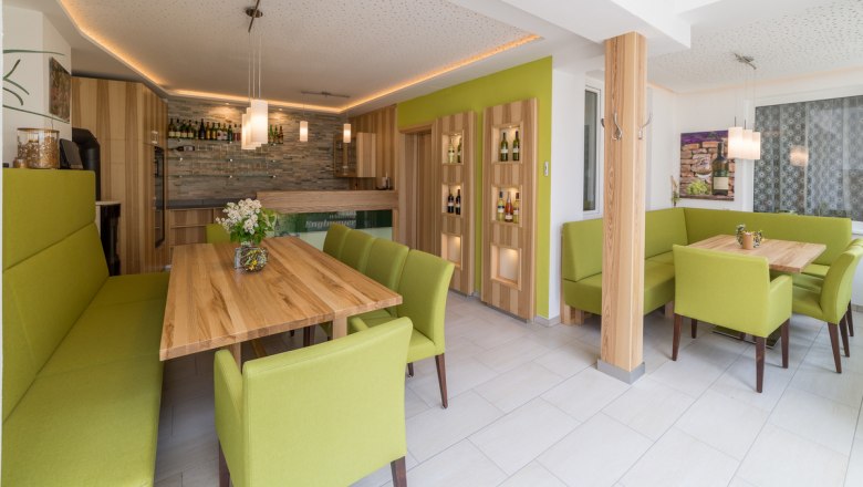 Moderner Verkostungsraum mit Holztischen und grünen Polstermöbeln.