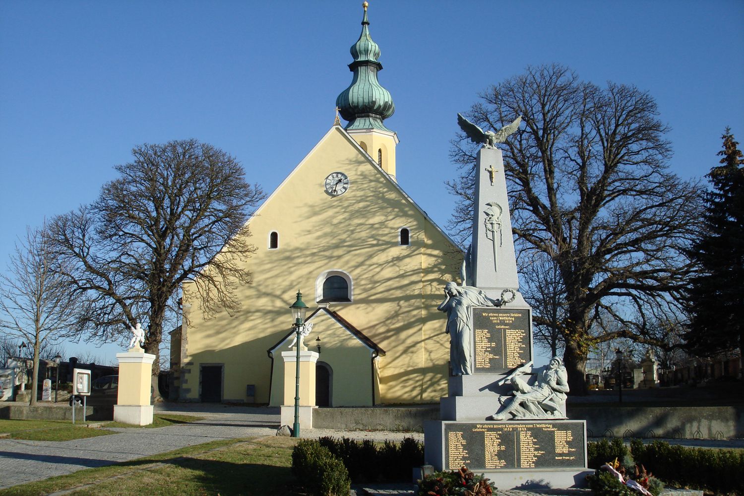 Pfarrkirche des heiligen Hippolyt mit Kriegerdenkmal im Vordergrund.