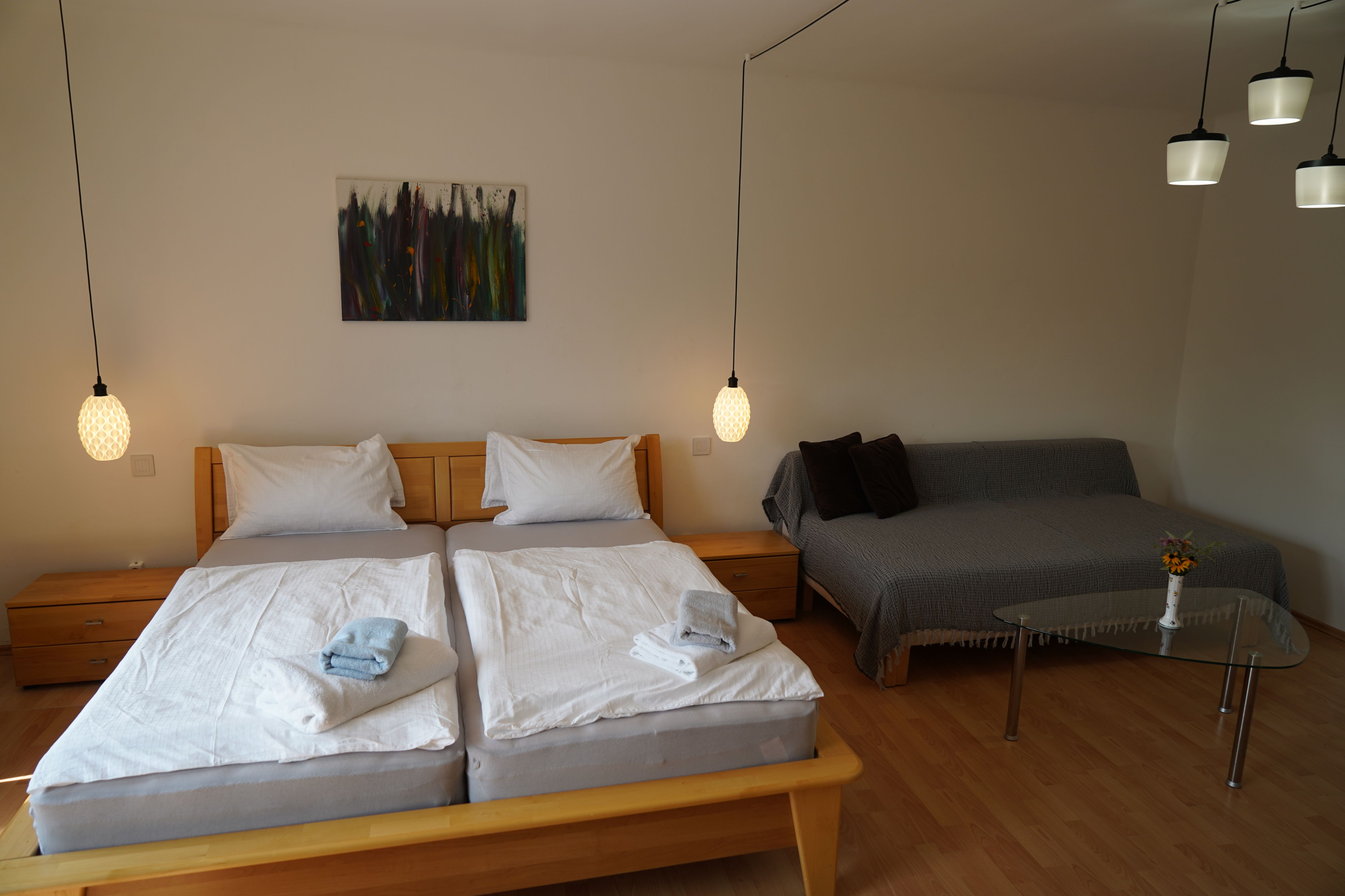 Cozy bedroom with double bed, sofa and glass table.