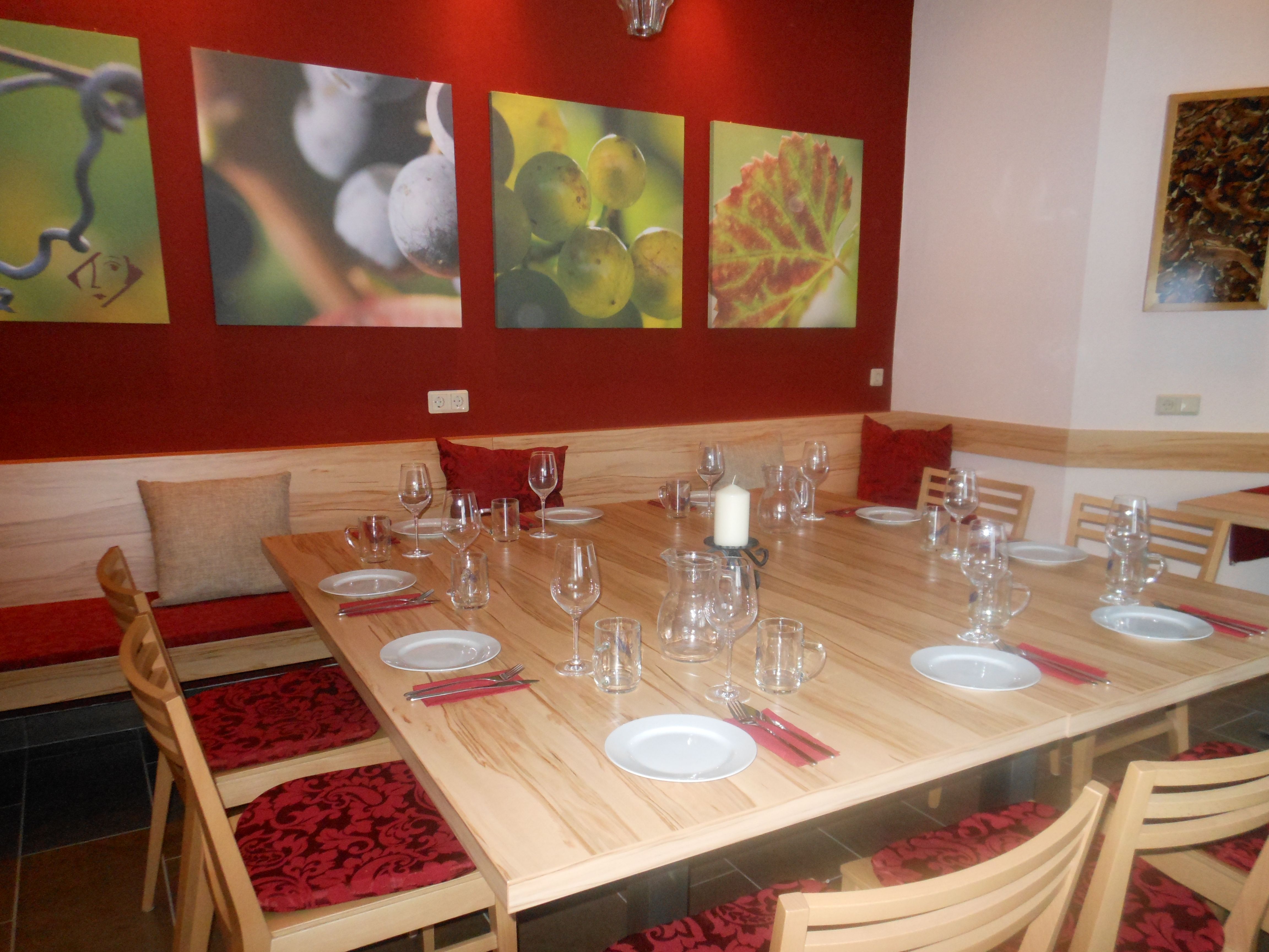 Ein Verkostungsraum mit gedecktem Holztisch, Weingläsern und Wandbildern von Weintrauben.