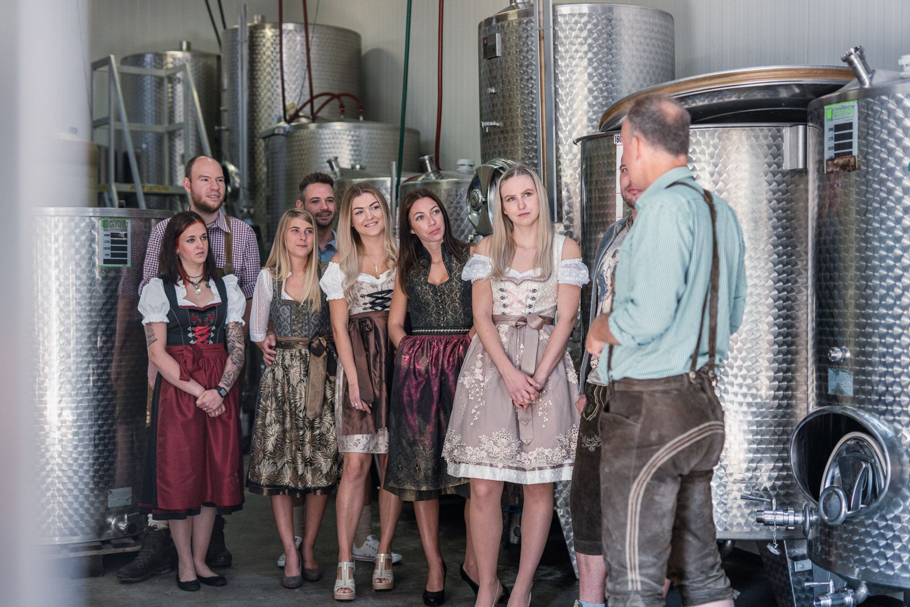 Gruppe von Menschen in traditioneller Kleidung in einer Weinkellerei.
